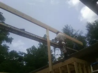 Carpenter setting a ridge beam over a new addition frame — Ice Dam Removal by Roofing Brothers in Mc Allister