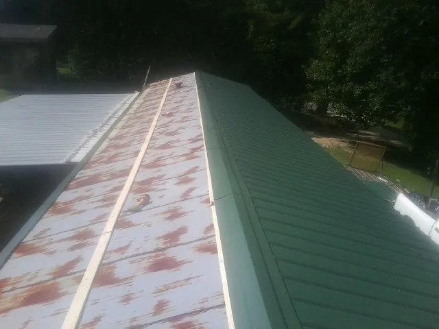 Old rusted panels beside newly installed green metal roofing — Wind Damage Roof Repair by Roofing Brothers in Mc Allister