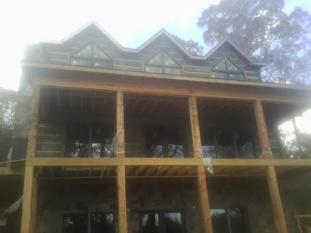 Dormers and porch framing on a large log home under construction — Roof Coating work by our crew in Mc Allister