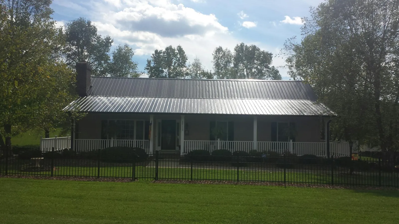 Gray metal roof on a brick ranch with a full width front porch — Gutter Guard Installation work by our crew in Mc Allister