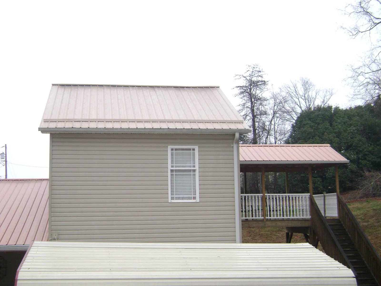 Tan metal roofs on a two story addition and attached porch, from a Roof Replacement job in Mc Allister