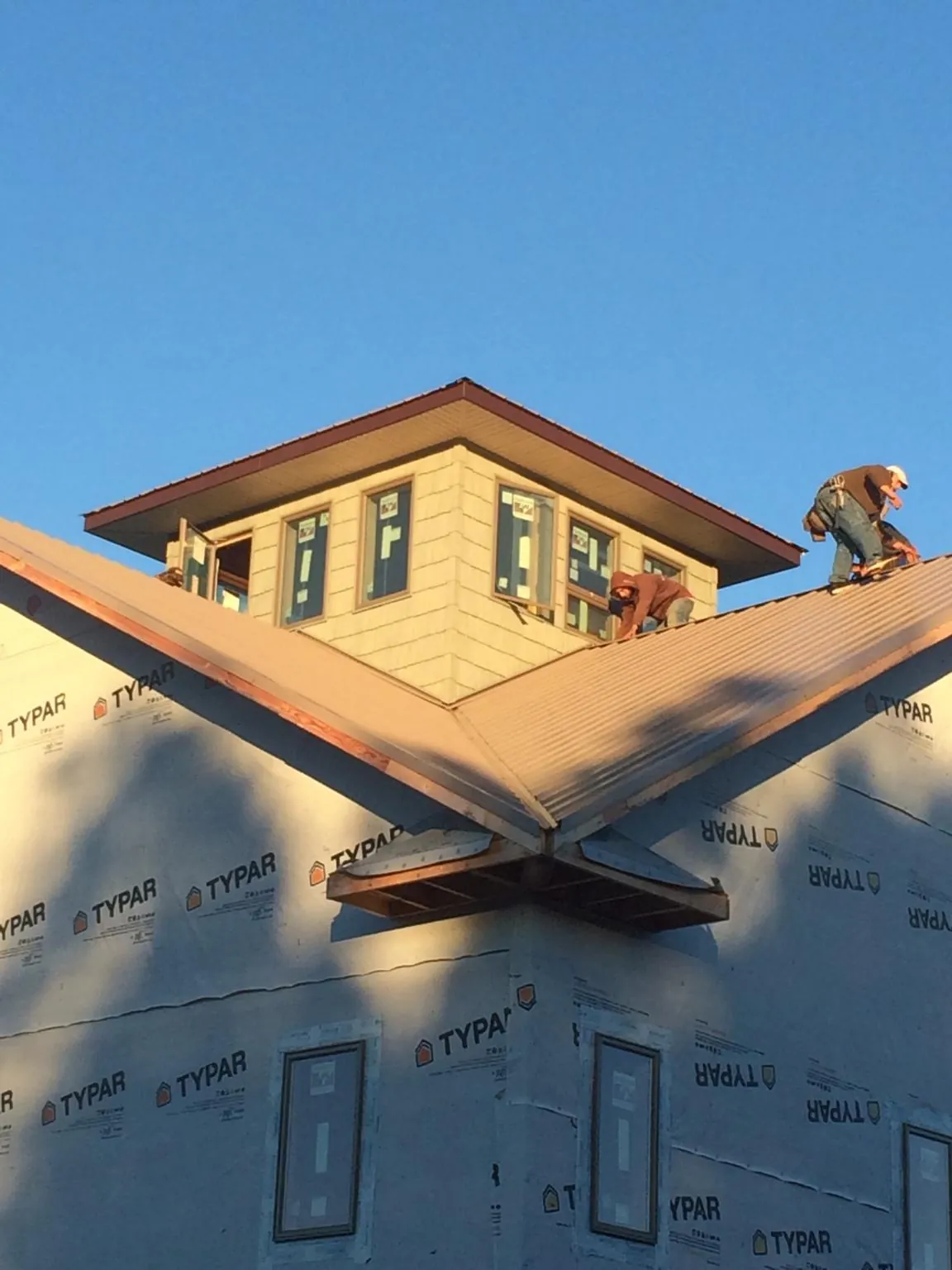 Roofers working around a rooftop cupola on a new metal roof at sunset — Roof Waterproofing in Mc Allister by Roofing Brothers